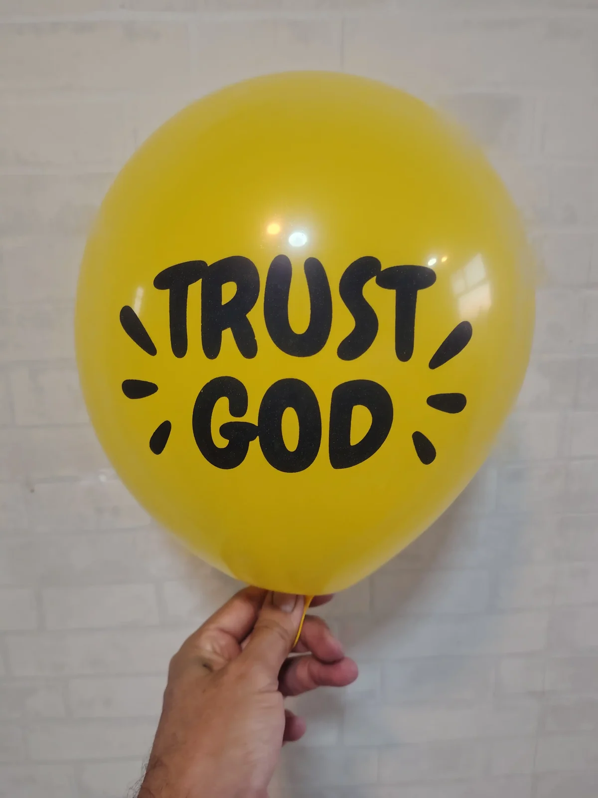 Balão amarelo com a mensagem Trust God em preto
